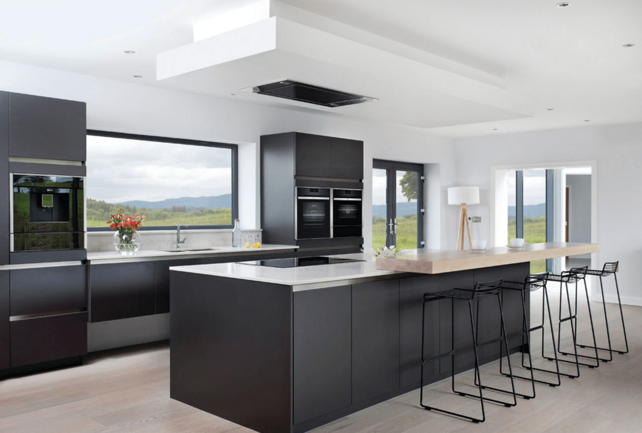 Een zwarte keuken met een betonlook keukenblad.